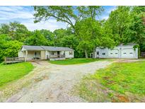 Charming single-story home with a covered porch, detached garage, and a lush green surroundings at 3512 N Wakeland Rd, Paragon, IN 46166
