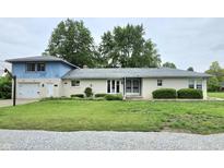 Charming brick home with a two-car garage, well-maintained lawn, and beautiful landscaping at 404 E Madison St, Alexandria, IN 46001
