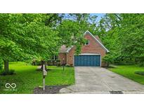 Charming brick home with a blue garage door, a well-manicured lawn, and mature trees providing shade at 5558 Spicebush Dr, Indianapolis, IN 46254