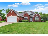 Charming single-story red brick home featuring an attached two-car garage and lush green lawn at 7521 Kilbarron Cir, Indianapolis, IN 46217