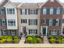 Three beautiful brick and tan townhomes showcase well manicured lawns and symmetrical windows at 9090 Demarest Dr, Fishers, IN 46038