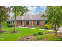 A well-maintained brick home featuring a stone accent, lush lawn, and mature landscaping in a tranquil setting at 1633 W 200 North, Greenfield, IN 46140