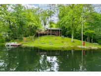 Secluded lake house with a dock and lush green surroundings reflecting beautifully in the calm water at 429 E Hoover Dr, Nineveh, IN 46164
