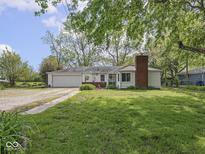 Charming single-story home with a brick chimney, attached garage, and a well-maintained lawn and landscaping at 4305 Clinton St, Lawrence, IN 46226