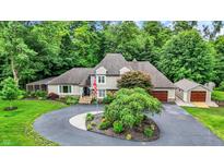 Stunning two-story home with a circular driveway, mature trees, and an American flag at 4623 E Windsor Ln, Columbus, IN 47201