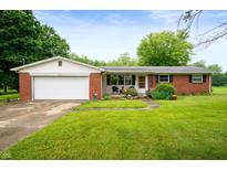 Charming brick ranch-style home featuring a well-manicured lawn, attached garage, and cozy front porch at 8027 S 250 E, Markleville, IN 46056
