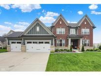 Beautiful two-story brick home featuring a three-car garage and well-manicured lawn at 15023 Glenmoor Cir, Carmel, IN 46033