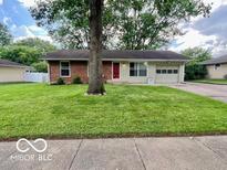 Charming single-story home featuring a red door, attached garage, and a lush green lawn at 1834 Chandler Ln, Columbus, IN 47203