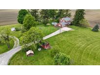 Expansive aerial view of a red brick two-story home surrounded by lush green lawns, mature trees and outbuildings at 4817 N 150 W, Anderson, IN 46011