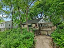 Quaint exterior view of home featuring a greenhouse and unique architectural details, enveloped by lush greenery at 5035 Boulevard Pl, Indianapolis, IN 46208