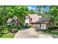 Charming red brick home with a three-car garage and mature trees, providing shade and curb appeal at 5953 Deer Hollow Ct, Pittsboro, IN 46167