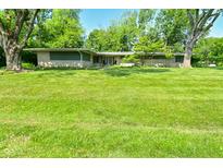 Single story ranch home featuring mature trees and a well manicured lawn at 6550 Sunset Ln, Indianapolis, IN 46260