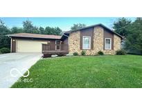 Charming single-story home featuring a stone facade, cozy porch, and attached two-car garage at 865 Countryside Ln, Columbus, IN 47201