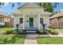Charming home featuring a covered front porch with vibrant plants and a freshly painted teal front door at 923 42Nd St, Indianapolis, IN 46205