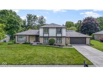 Charming two-story home featuring stone accents, gray shingles, a well-manicured lawn, and attached garage at 10502 E Lakeshore Dr, Carmel, IN 46033