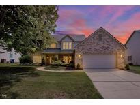 Charming two-story home with brick accents, attached garage, and a well-manicured lawn under a beautiful sunset sky at 10965 Fairway Ridge Ln, Fishers, IN 46037