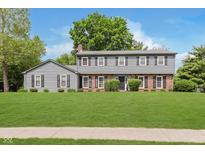 Traditional two-story home with gray siding, brick accents, manicured lawn, and mature trees at 12112 Roxbury Pl, Carmel, IN 46033
