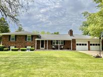 Charming single-story brick home featuring a well-manicured lawn and an attached two car garage at 1579 Crest Dr, Shelbyville, IN 46176
