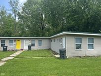 Modest exterior of a multi unit building featuring neutral siding, a bright yellow front door, and lawn at 1642 W 6Th St, Anderson, IN 46016