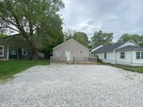 Charming single-story home with a large gravel driveway and a cozy front porch, enveloped by lush trees at 2608 S Rybolt Ave, Indianapolis, IN 46241