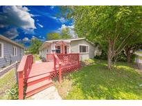 Charming home featuring a red deck and lush green yard with mature trees at 3220 Newton Ave, Indianapolis, IN 46201