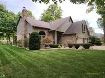 Charming two-story home with brick facade, attached two-car garage and manicured front lawn at 3819 S Village Dr, New Palestine, IN 46163