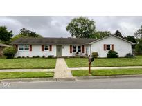 Charming single story home featuring a well maintained lawn, painted brick, and wood trim accents at 4625 Woodcrest Dr, Columbus, IN 47203