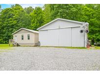 Side exterior view of the vinyl sided home and metal outbuilding, with a graveled parking area at 5858 N West Shore Dr, Morgantown, IN 46160