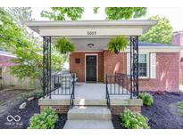 Charming covered front porch with decorative iron railings and beautiful hanging plants at 6005 Winthrop Ave, Indianapolis, IN 46220