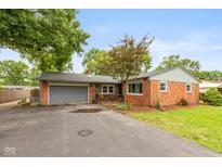 Charming single-story brick home featuring an attached garage and a cozy front patio at 615 E Stop 11 Rd, Indianapolis, IN 46227