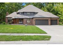 Charming brick home boasts a well-manicured lawn and three-car garage, nestled among mature trees at 6350 Red Oak Dr, Avon, IN 46123