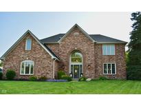 Charming brick home featuring an arched entry and beautifully landscaped front lawn with colorful flower beds at 6862 Riverside Way, Fishers, IN 46038