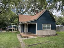 Charming blue home featuring a covered porch and well-maintained lawn surrounded by mature trees at 1206 Mcdougal St, Indianapolis, IN 46203