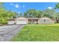 Charming ranch home featuring stone accents, attached garages, well-maintained lawn, and mature trees at 12121 East 21St St, Indianapolis, IN 46229