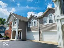 Beautiful townhome featuring a two-car garage, gray siding and a well-manicured lawn underneath a bright blue sky at 1280 Shadow Ridge Rd, Indianapolis, IN 46280