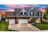 Beautiful two-story home featuring a three-car garage and well-manicured lawn at dusk at 13766 Heatherfield Dr, Fishers, IN 46038