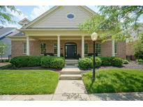 Charming brick home with manicured lawn, mature bushes, and inviting covered front porch at 2223 Shaftesbury Rd, Carmel, IN 46032