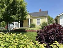 Charming yellow home with a well-manicured lawn and mature trees in a desirable neighborhood at 407 N Alton Ave, Indianapolis, IN 46222