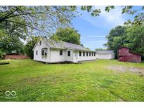 View of charming home with green lawn, separate garage, and an old-fashioned red barn at 4255 N County Road 1025 E, Indianapolis, IN 46234