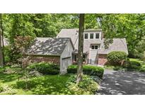 Brick home featuring an attached garage, manicured lawn, and lush landscaping at 7426 Shadow Wood Dr, Indianapolis, IN 46254