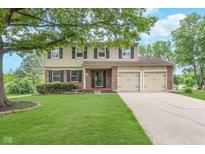 Inviting two-story home with a well-manicured lawn, mature tree, and a two-car garage at 8205 Picadilly Ln, Indianapolis, IN 46256
