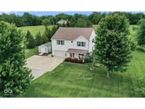 A charming two-story home, a lush green lawn, mature trees, storage shed, and basketball hoop at 11198 N 650 W, Fountaintown, IN 46130
