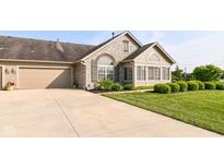 Charming stone house featuring a well-maintained lawn, a two-car garage and meticulously kept front yard landscaping at 13807 Rue Fontaine Ln, McCordsville, IN 46055
