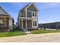 Charming two-story home featuring a welcoming porch, a well-manicured lawn, and fresh flowers at 1405 Deloss St, Indianapolis, IN 46201