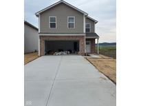 Two-story home featuring a brick and vinyl exterior, a spacious two-car garage, and a concrete driveway at 1441 Elm St, Martinsville, IN 46151