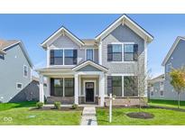 Charming two-story home showcasing a welcoming front porch, manicured lawn, and stylish architectural details at 1694 Windrush Pl, Westfield, IN 46074