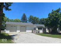 Charming single-story home featuring a two-car garage, gravel driveway, and well-maintained lawn against a bright blue sky at 1882 Knox Dr, Clayton, IN 46118