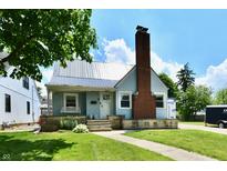 Charming home with a metal roof, brick chimney, and a well-maintained lawn on a sunny day at 209 E John St, Alexandria, IN 46001