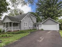 Charming gray home with a white-railed porch, mature trees, and a two-car detached garage at 70 Fairground St, Franklin, IN 46131