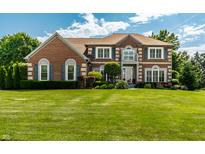 Beautiful brick home with manicured lawn and lush landscaping on a sunny day at 14149 Ledgewood Way, Carmel, IN 46032